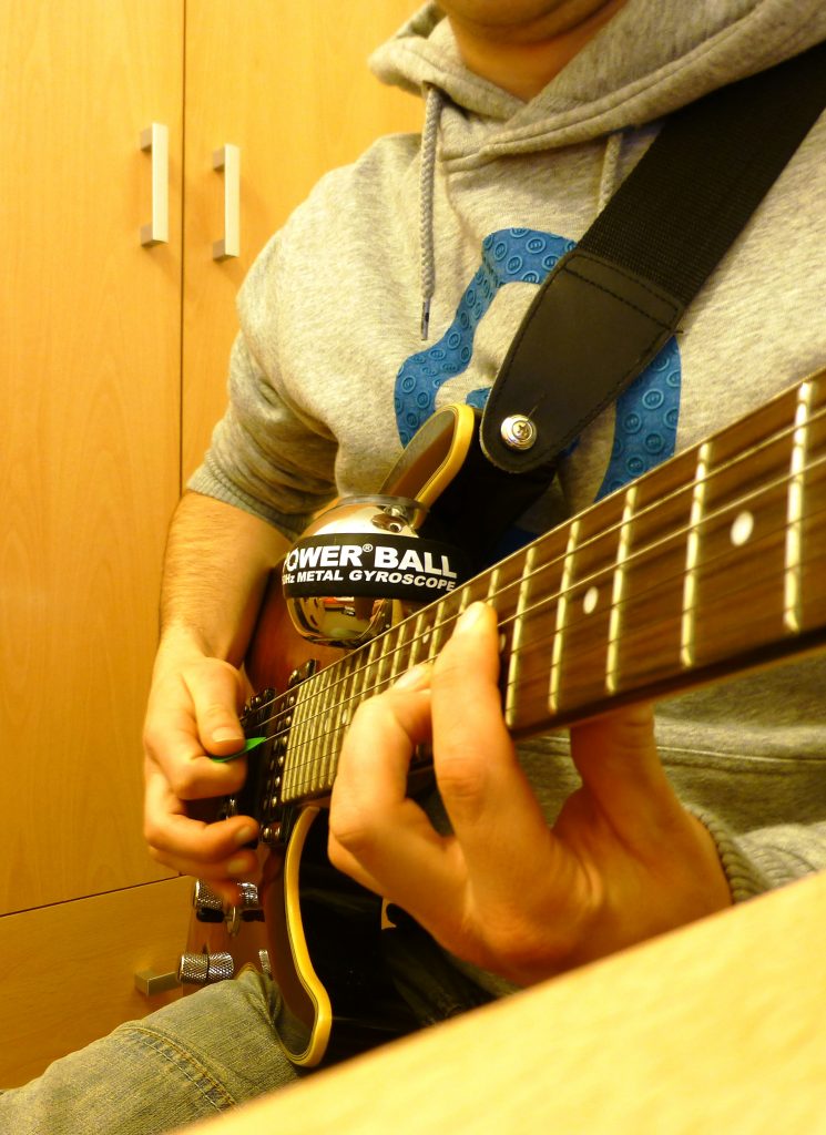 Man playing Guitar with Powerball to relieve RSI from guitar 