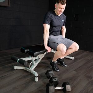 Man with Hex Dumbbells sitting on weights bench in home gym