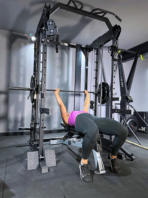 Woman performing bench press on power rack