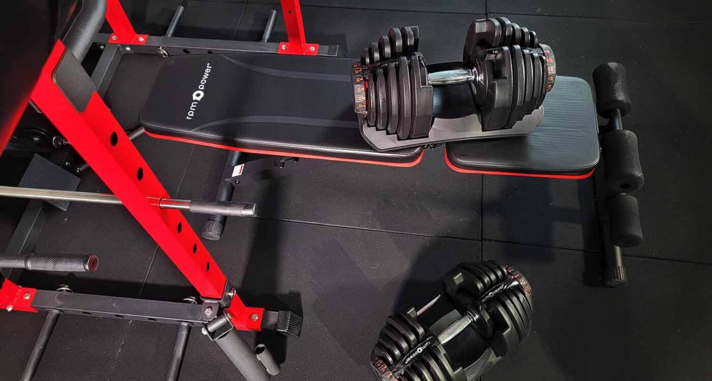 RPM Power 40kg multi-level dumbbells on a P1100 weight bench with a red rack in the background.
