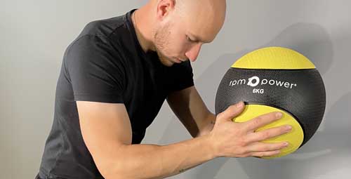 A man holding the 4kg yellow medicine ball.