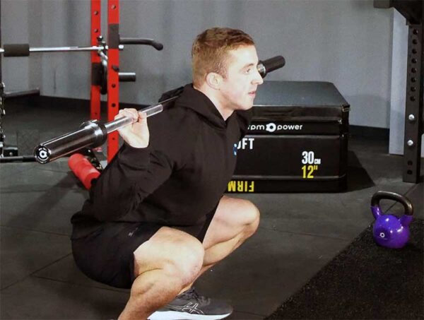 Personal trainer Ian McGarry squatting with barbell bar
